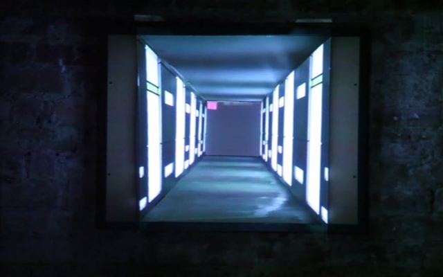 Video still: a glowing corridor that appears to recede into a brick wall