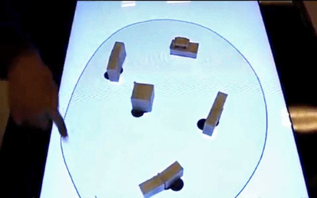Small tangible robots on a lit interactive table